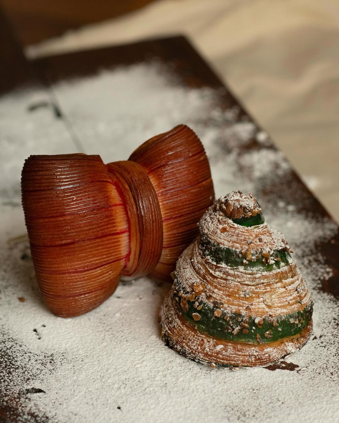 Glossy, finely-piped pastry dusted with icing sugar on a dark board