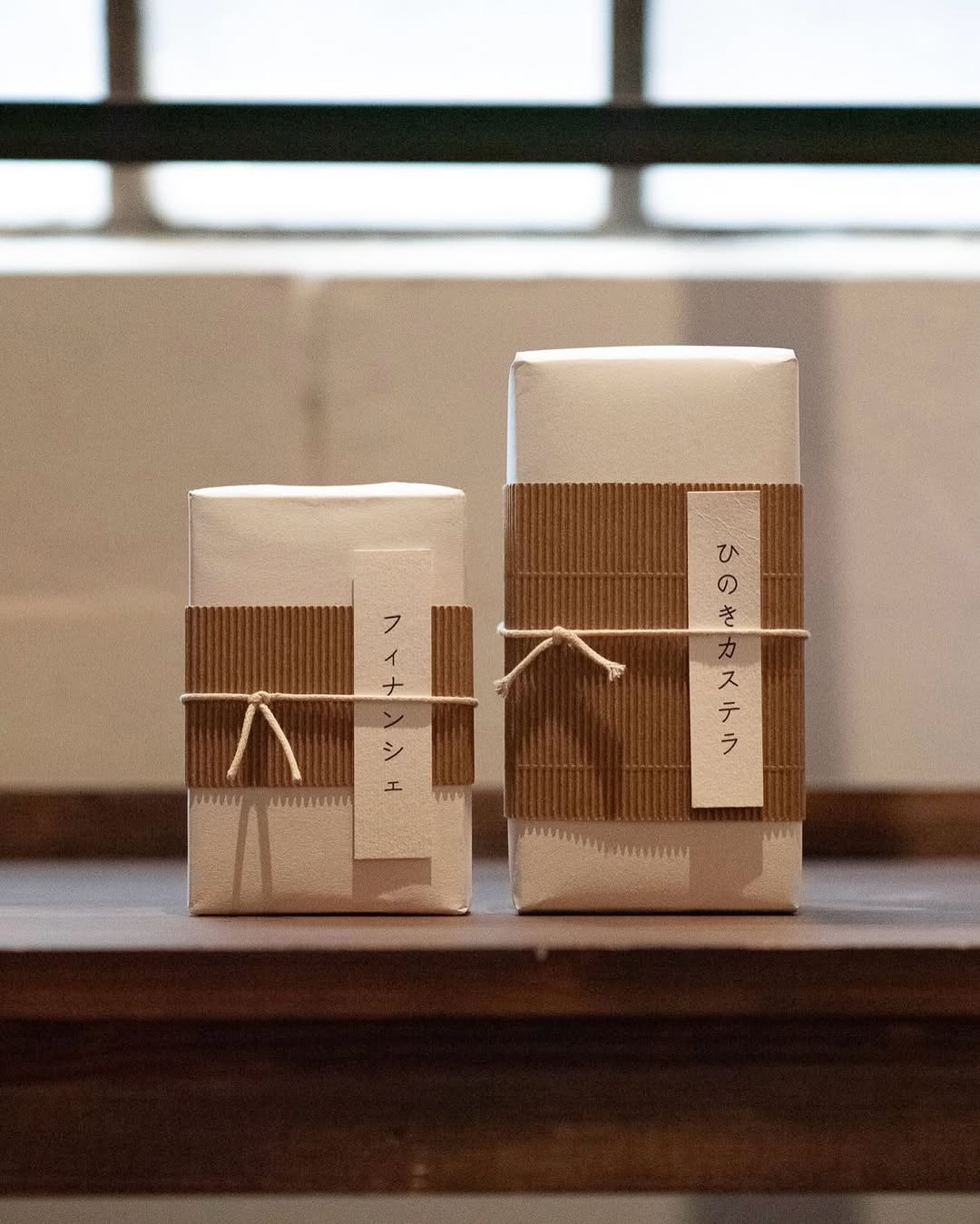 Two pastries wrapped in white paper with corrugated bands and Japanese labels